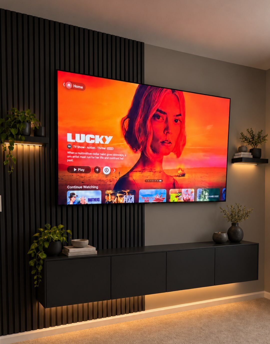 Wall-mounted television on a black slatted wood wall with a floating black cabinet.