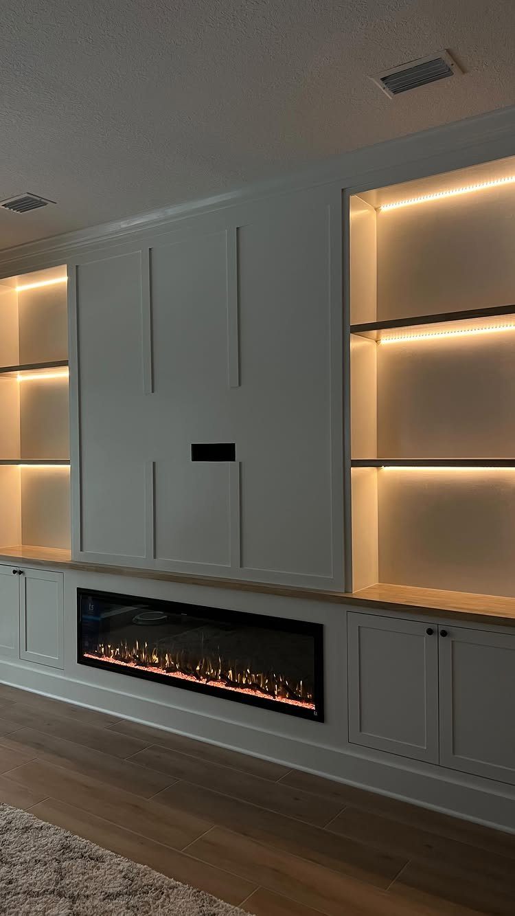 White custom built-in shelving and cabinets with integrated lighting and a linear fireplace.