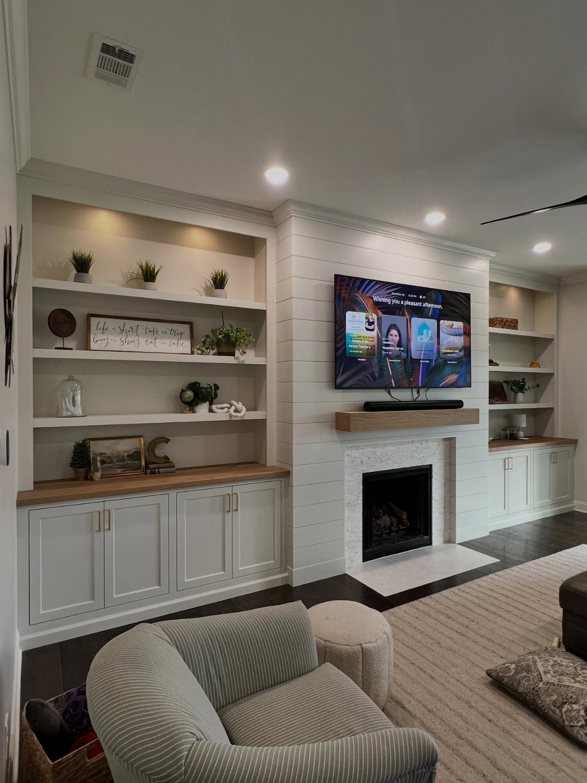 White painted built-in cabinets and shelving surrounding a modern white shiplap fireplace.