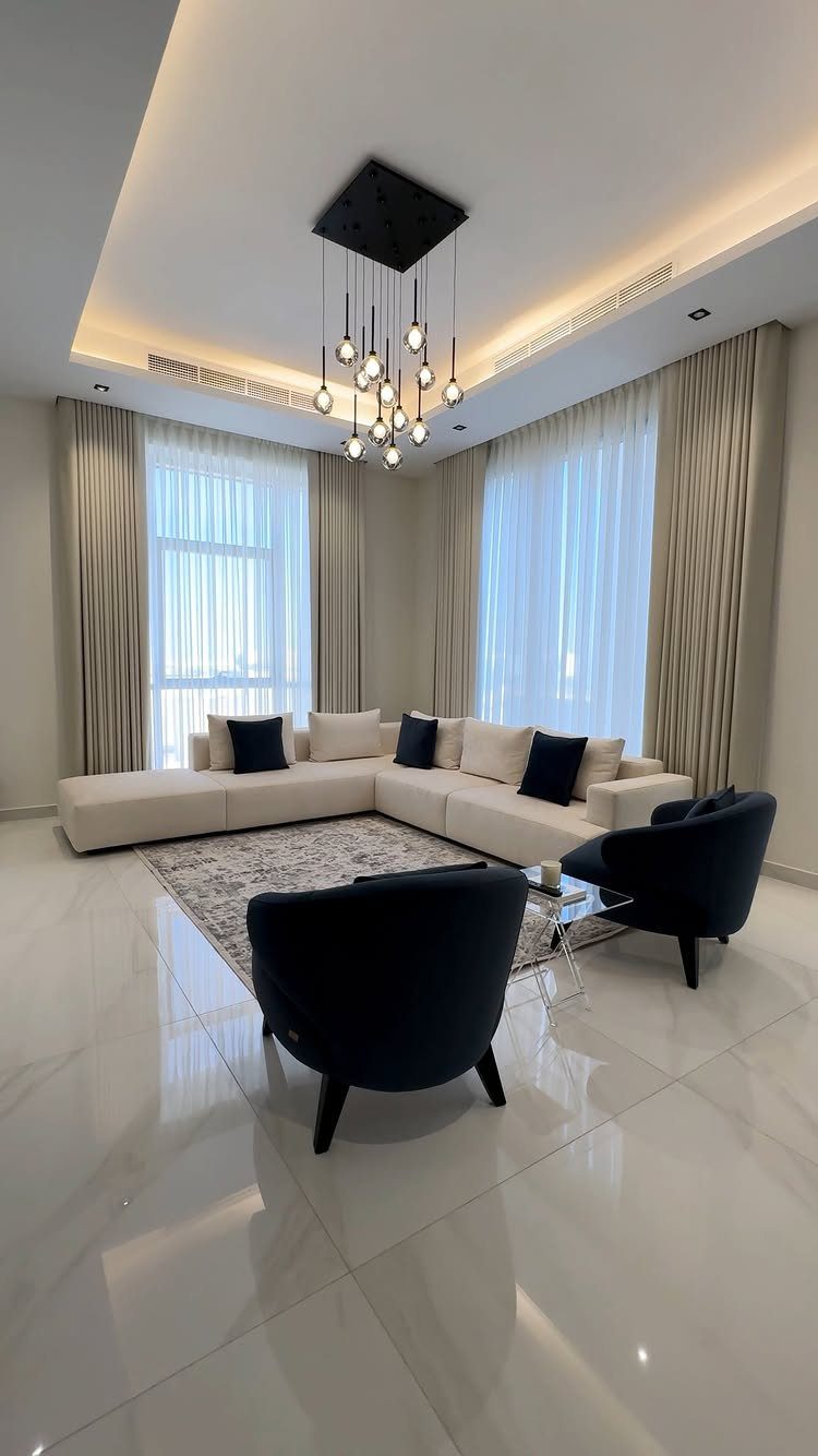 Modern living room with cream sectional sofa and dark navy blue accent chairs.