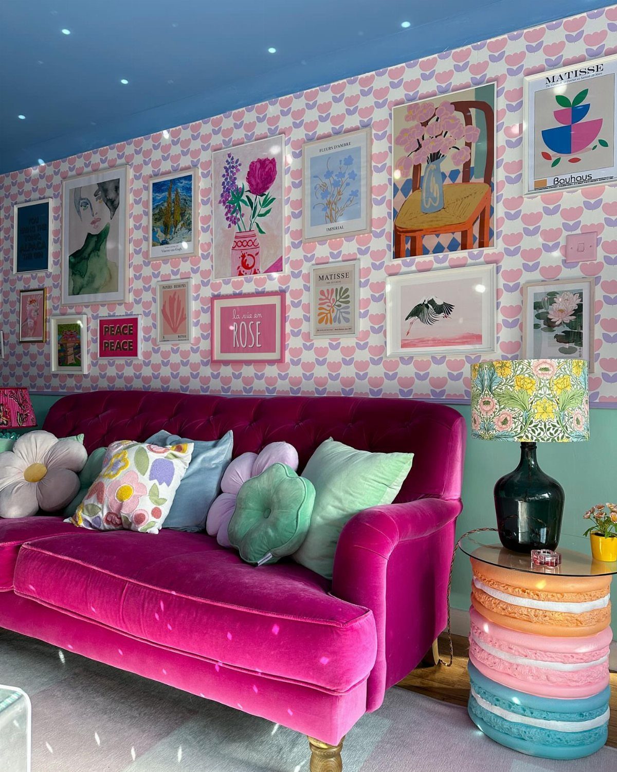 Magenta velvet sofa in a room with pink patterned wallpaper and blue ceiling
