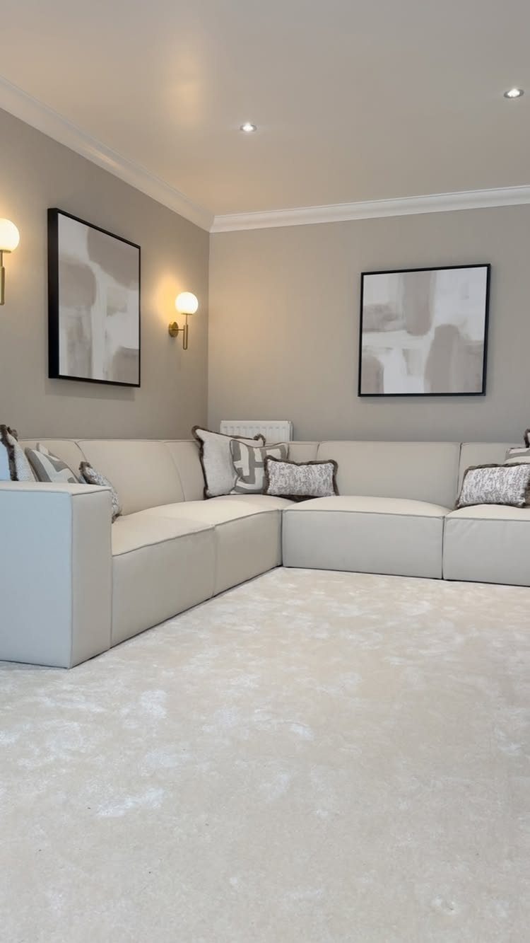 Cream L-shaped sofa in a monochromatic beige living room with abstract wall art.