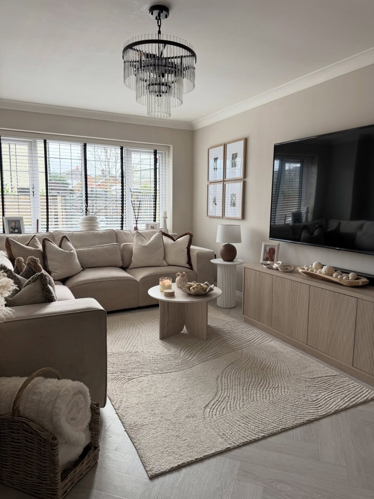 Beige living room with a neutral sectional sofa, textured rug, and wooden furniture.