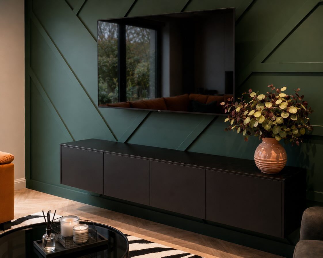 Dark green geometric accent wall with a black floating console and wall-mounted TV.