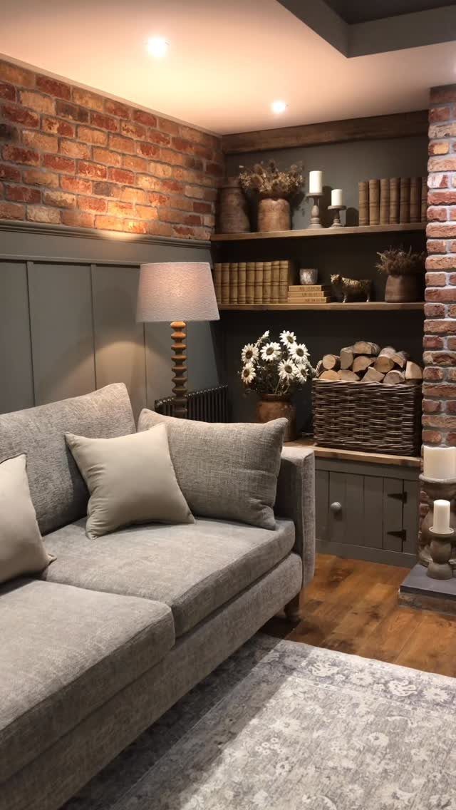 Grey sofa in a rustic room with brick walls and wooden shelving.