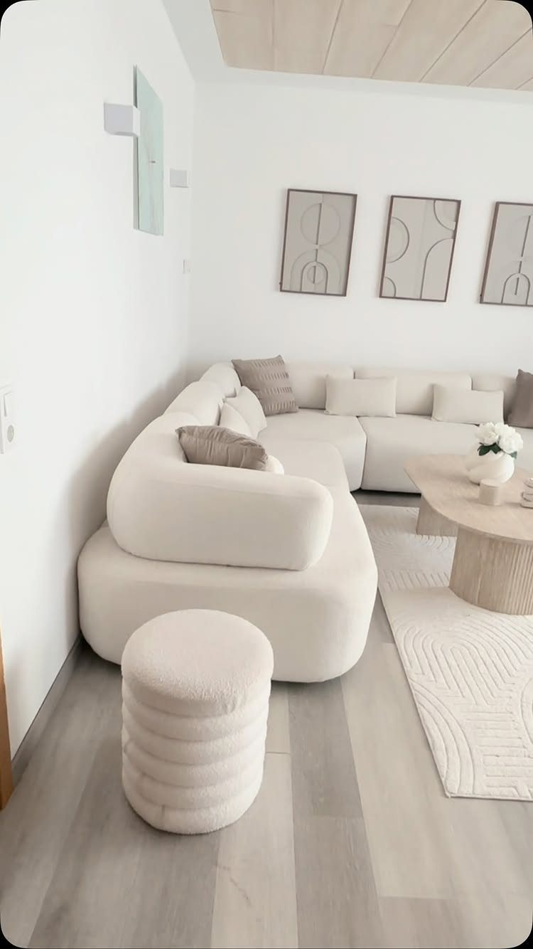 Curved white sofa and ribbed ottoman in a monochromatic white living room setting