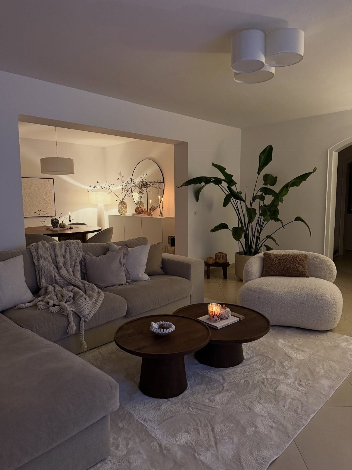 Low-profile grey sofa and rounded white oversized armchair in a cozy living room.