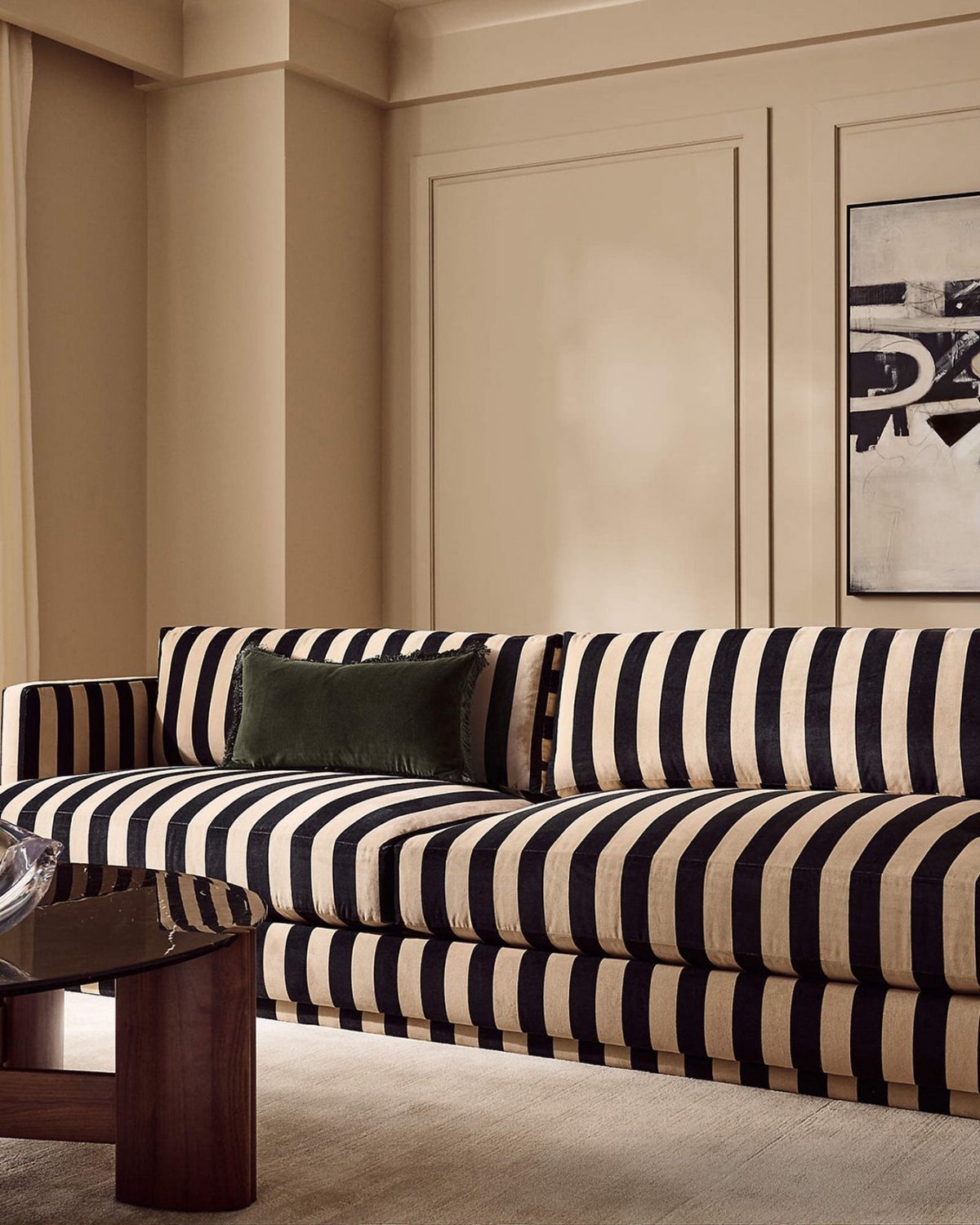 Striped sofa with a dark green velvet cushion in a beige living room.