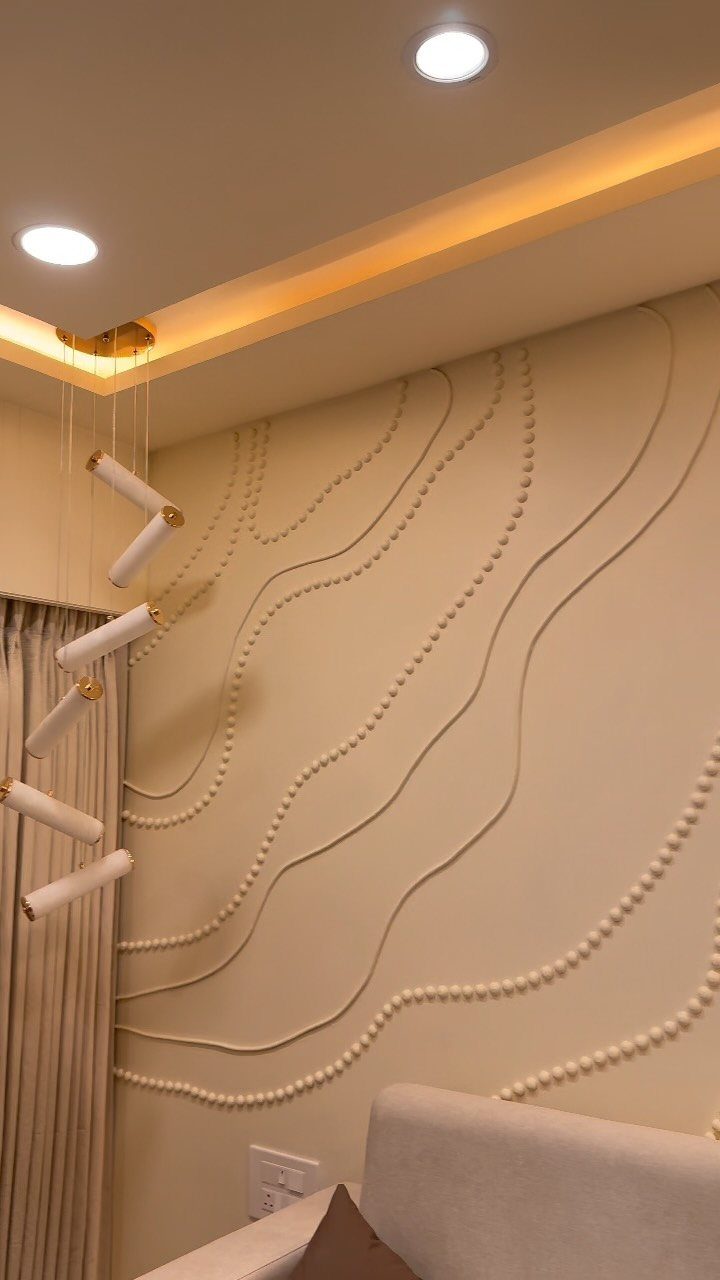 Beige living room wall with wavy 3D textured lines and modern pendant lighting.