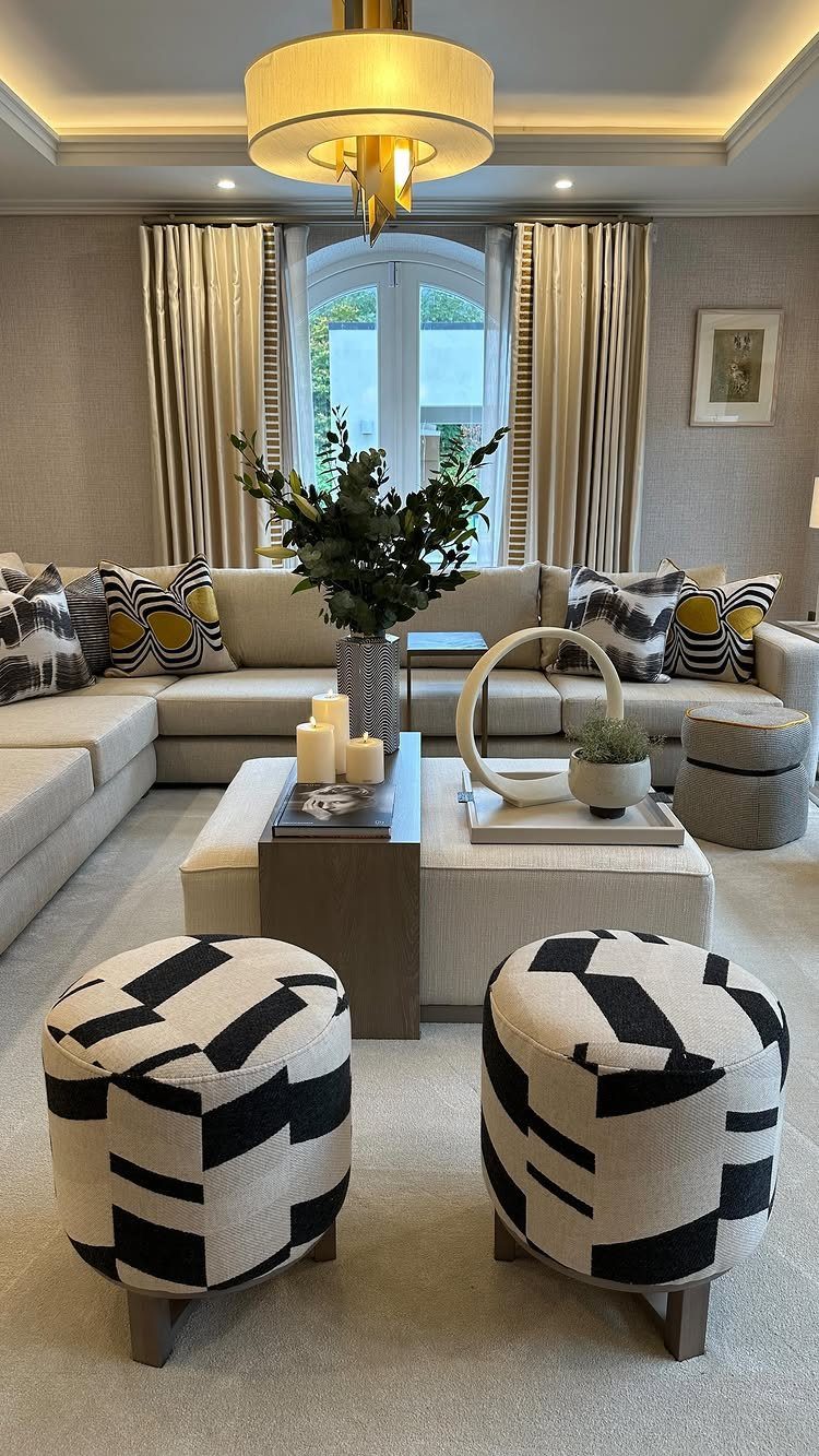 Modern living room with beige sectional sofa and black and white geometric ottomans.