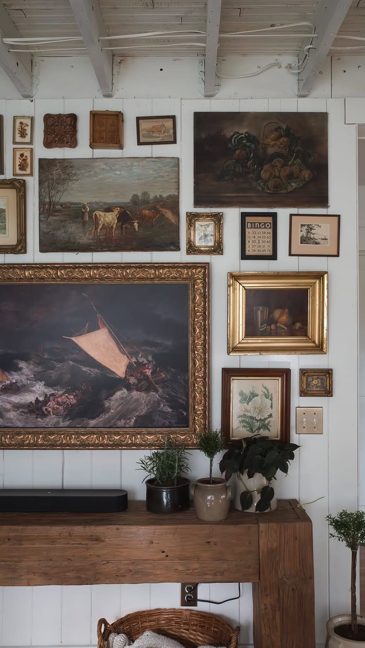Framed art and paintings arranged in a gallery wall above a wooden table.