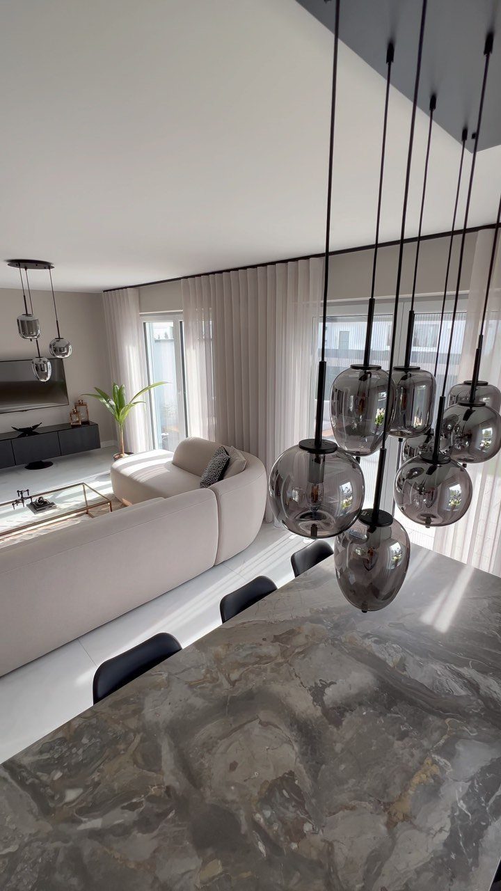 Modern living room with grey marble table, curved sofa, and grey pendant lights.