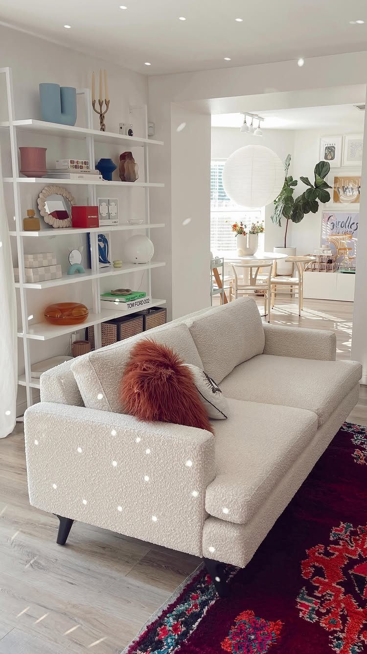 Cream bouclé sofa with a plush brown cushion on a red patterned rug.
