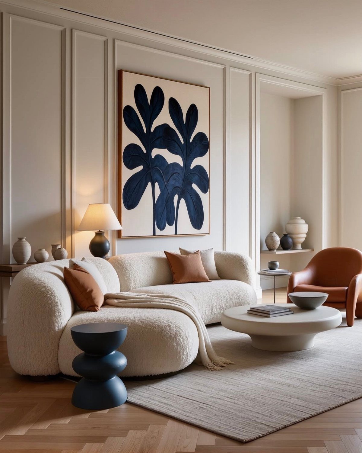 Curved white bouclé sofa in a modern living room with blue leaf artwork.