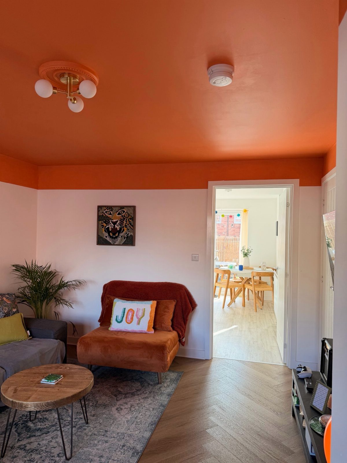 Living room with orange ceiling, brown velvet armchair, and round wooden coffee table.