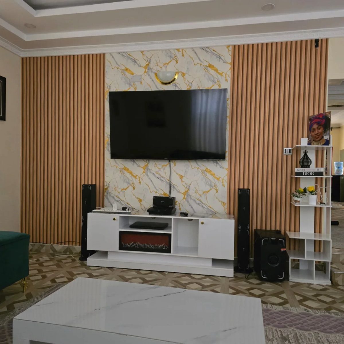 Modern living room with marble accent wall, wooden slats, and white furniture.