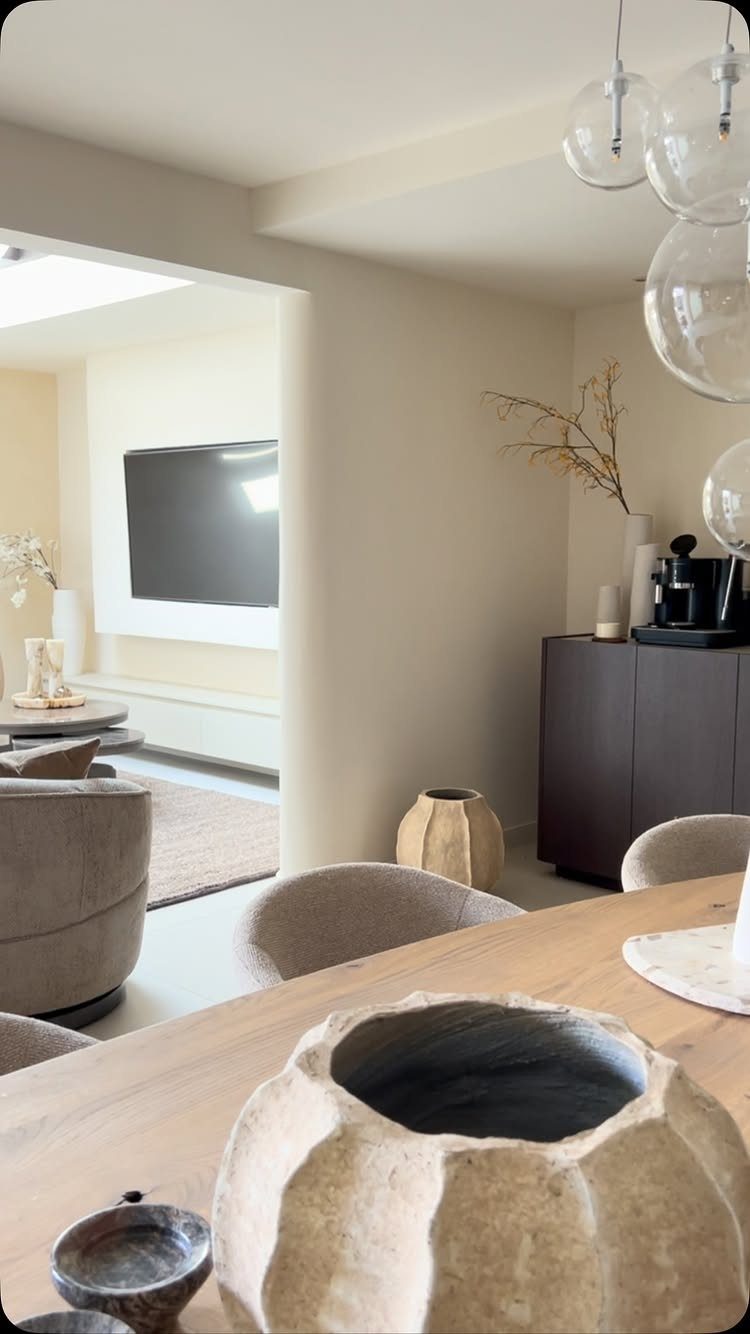 Light wood dining table with textured stone bowls in a neutral modern interior