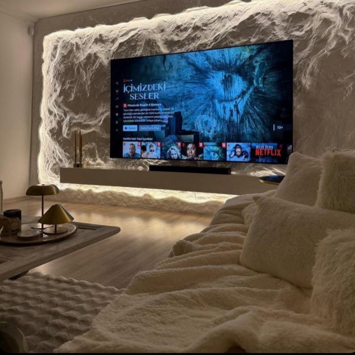 Textured white 3D wall covering with LED lighting behind a large television screen.