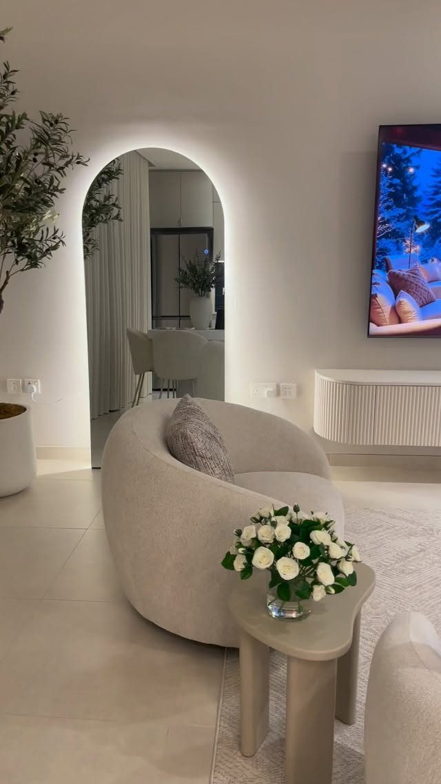 Rounded cream armchair and curved side table in a bright, modern living room