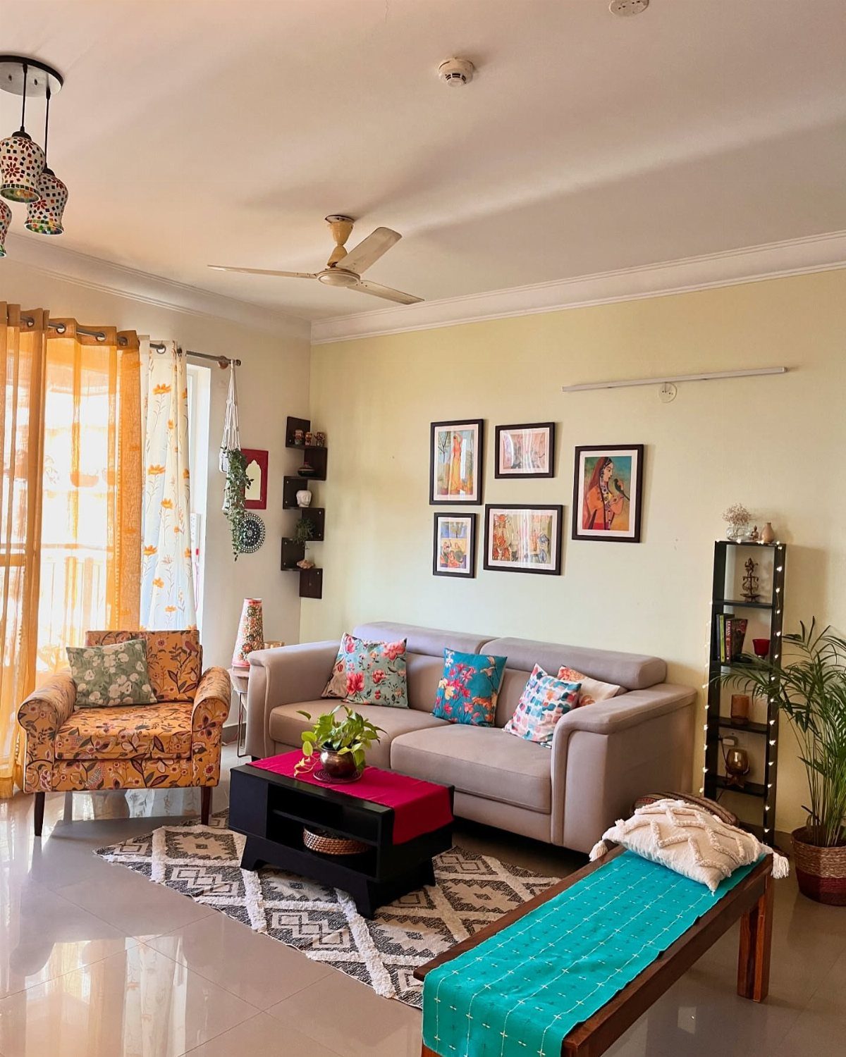 Small living room with grey sofa, patterned armchair, and colorful accent textiles.