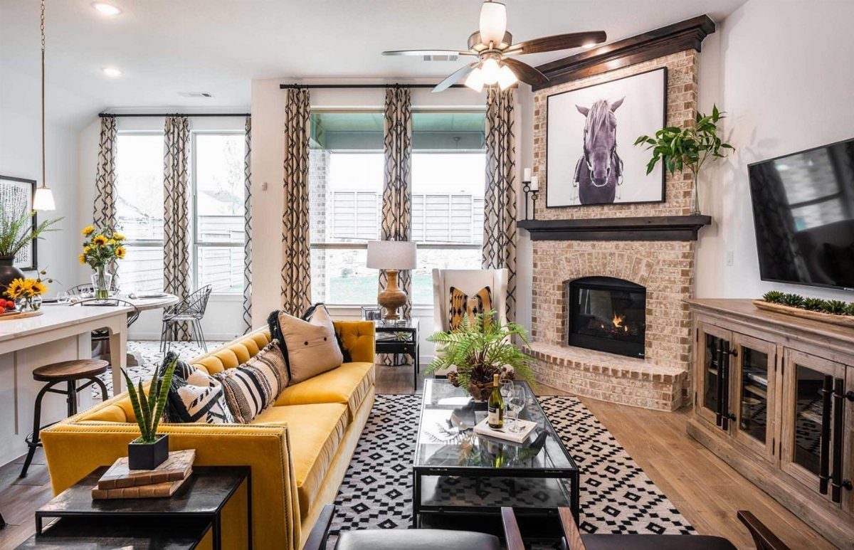 Brick fireplace with black mantel in a living room with yellow sofa