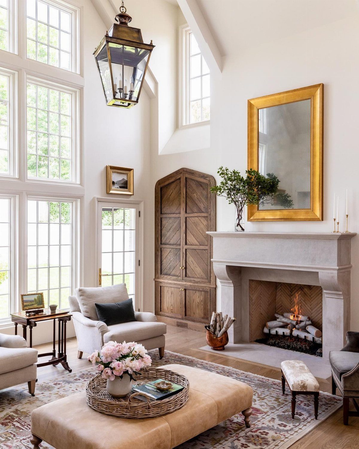 Light stone fireplace with a large gold mirror in a bright living room