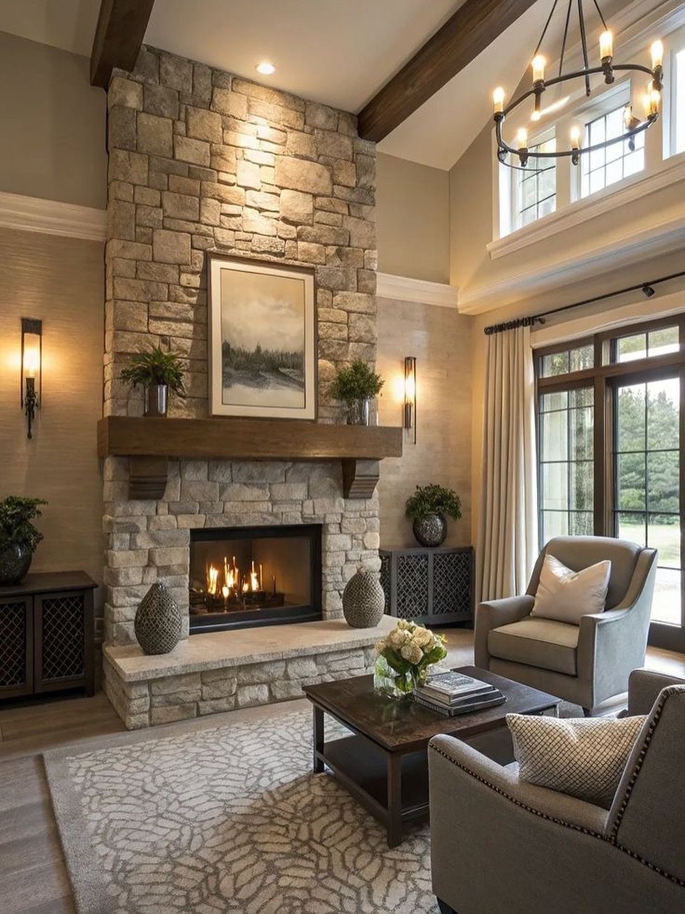 Stone fireplace with wooden mantel in a living room with grey armchairs.