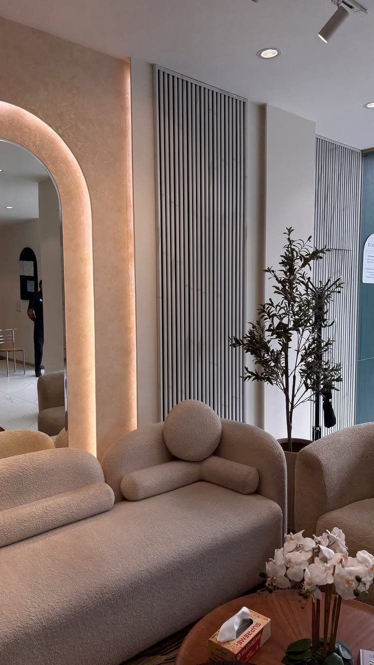 Curved beige sofa in a room with pink-toned clay walls and slatted panels.