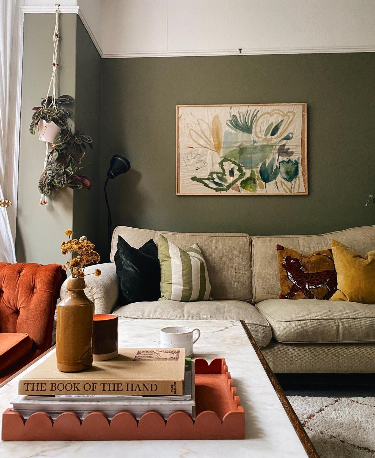 Living room with a mid-green accent wall, beige sofa, and marble coffee table.