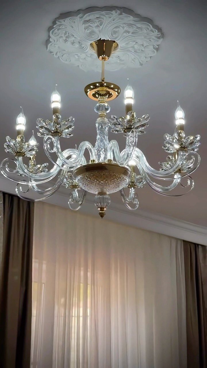 Ornate glass and gold chandelier hanging from a decorative white ceiling medallion.