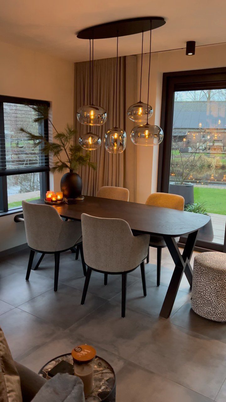 Glass globe pendant lights hanging over a dark wooden dining table in a modern room.