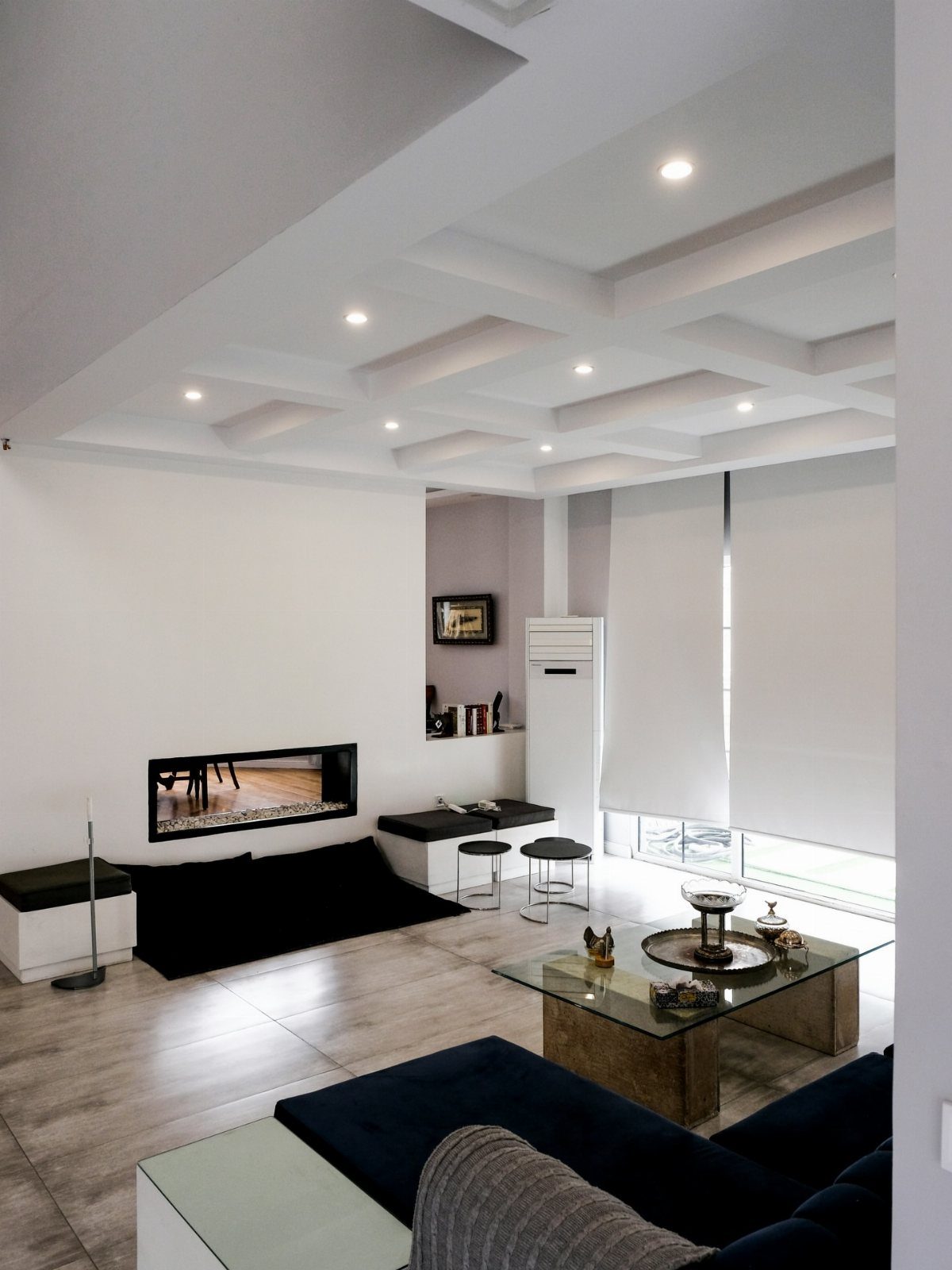 Modern living room with recessed lighting installed in a white coffered ceiling.
