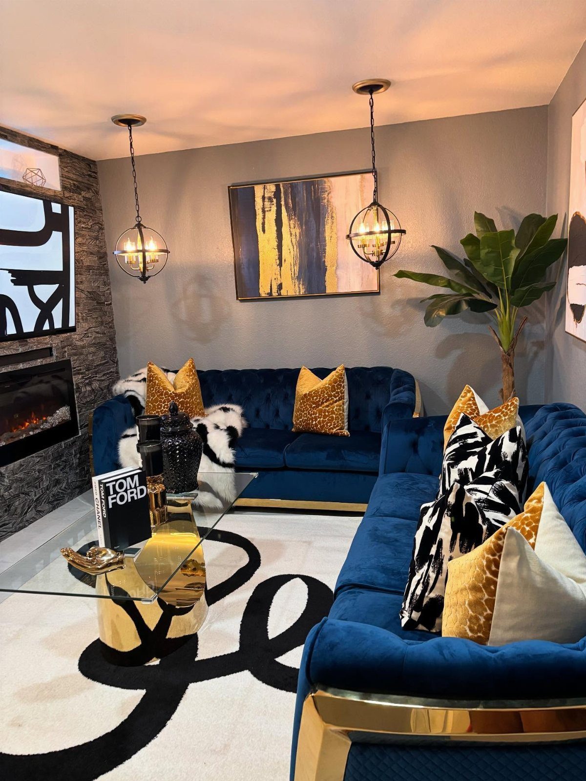 Deep blue velvet sofas in a living room with grey-blue walls and gold accents.