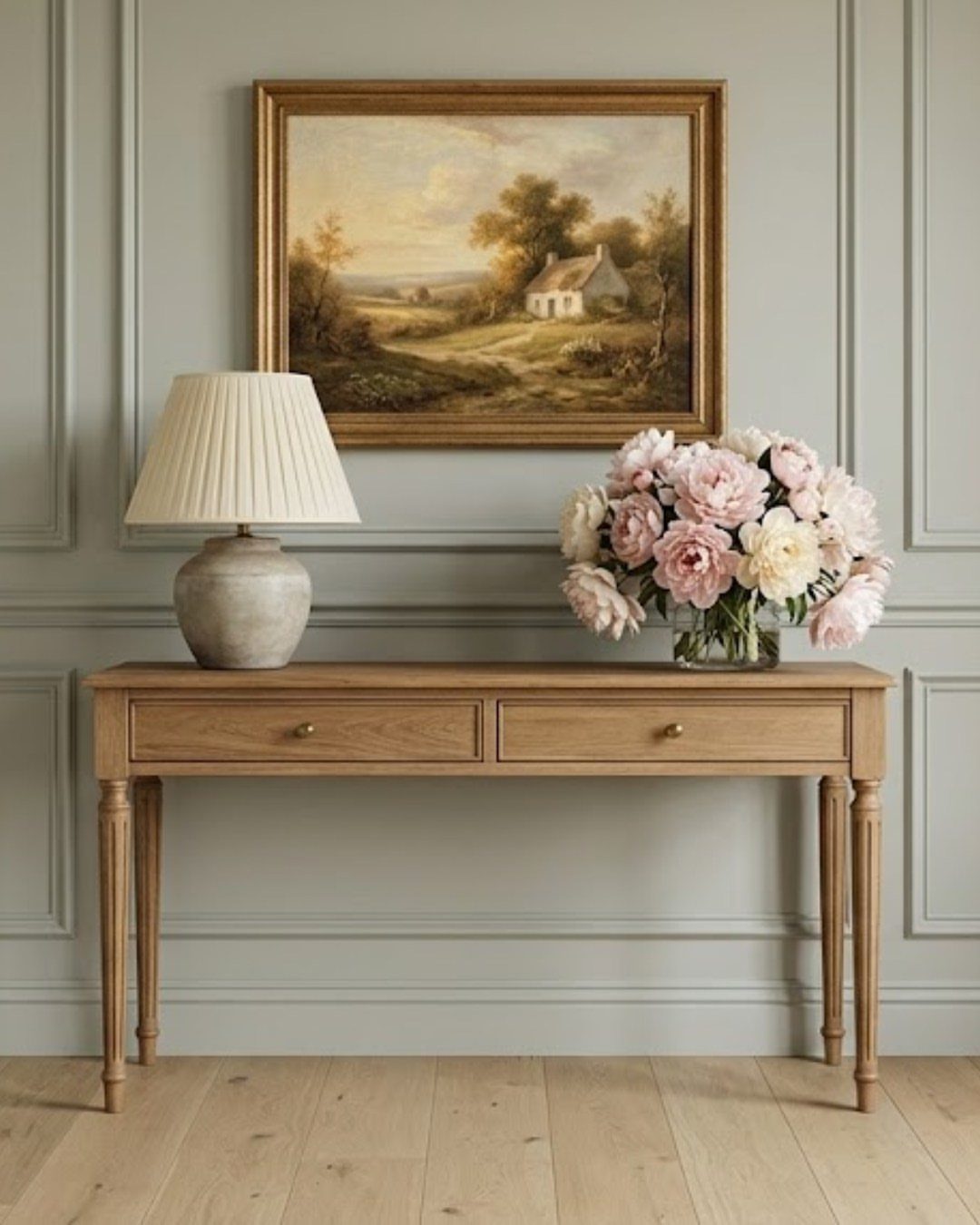 Sage green paneled walls with a wooden console table and floral arrangement.