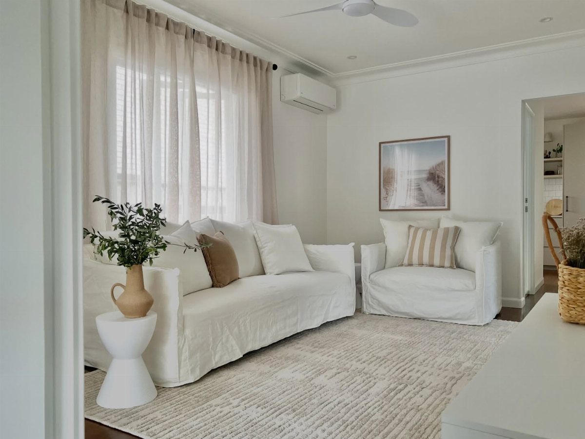 White sofas with front legs resting on a light grey textured living room rug