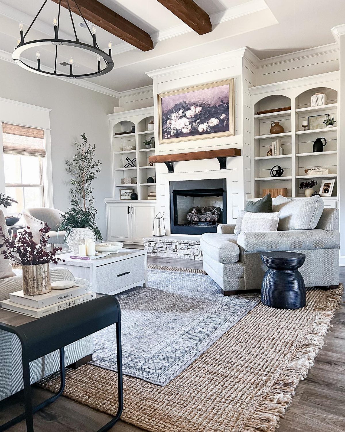 Layered rugs in a bright living room with a white sofa and fireplace.