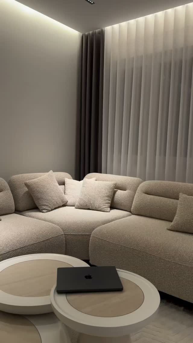 Beige sectional sofa with round white coffee tables in a modern living room