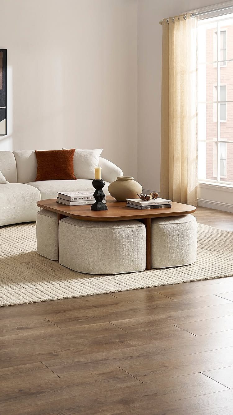 Low wooden coffee table with cream ottomans tucked underneath in a neutral living room