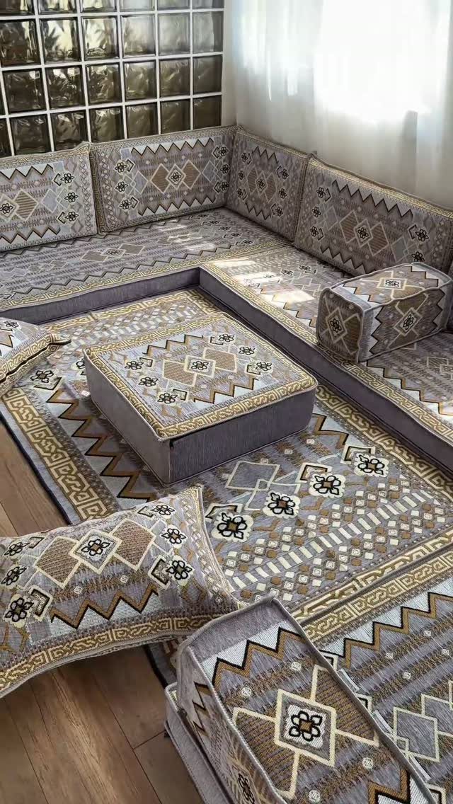 Patterned floor seating arrangement with a central square ottoman and matching cushions.