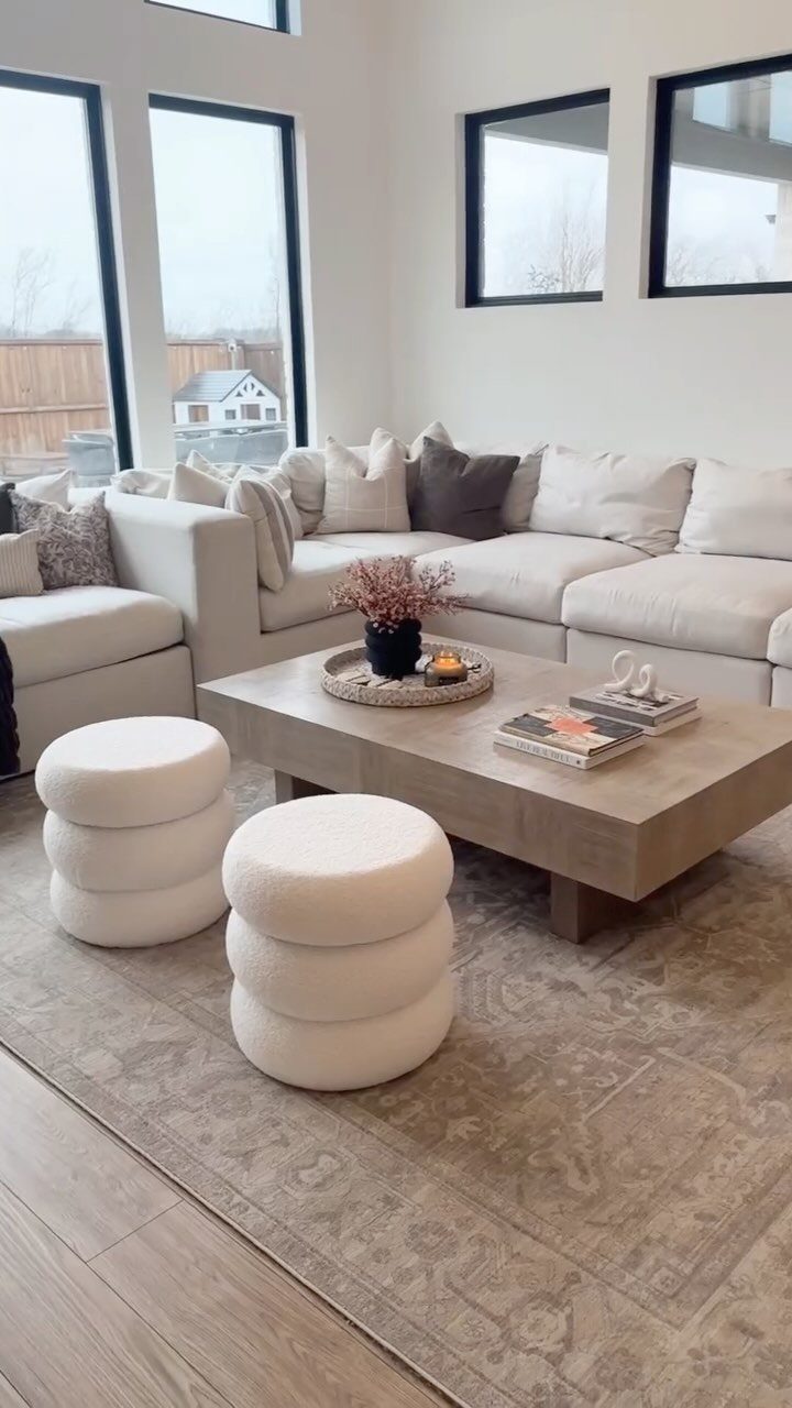 White tiered round ottomans next to a light wood coffee table and sectional sofa.