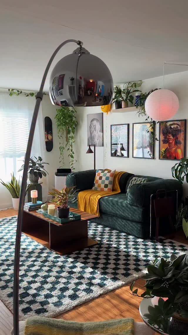 Green velvet sofa and checkered rug in a living room with eclectic art.