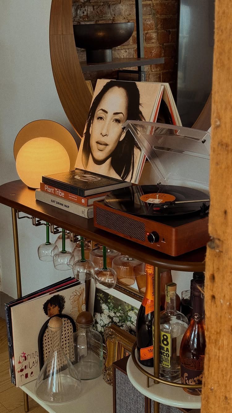 Wooden home bar shelf with record player, liquor bottles, and hanging wine glasses.