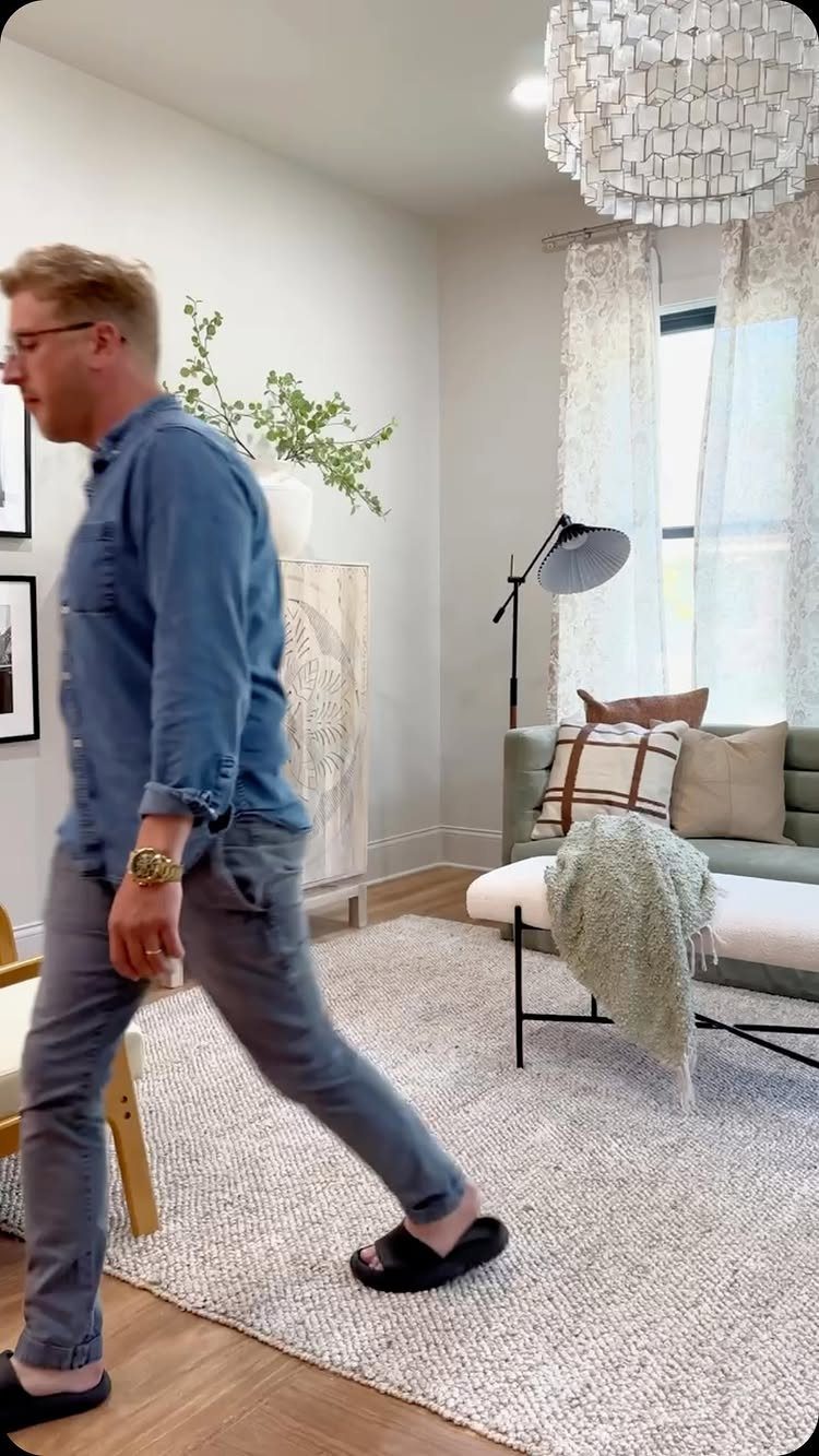 Man walking through a living room with a natural color palette and neutral decor.