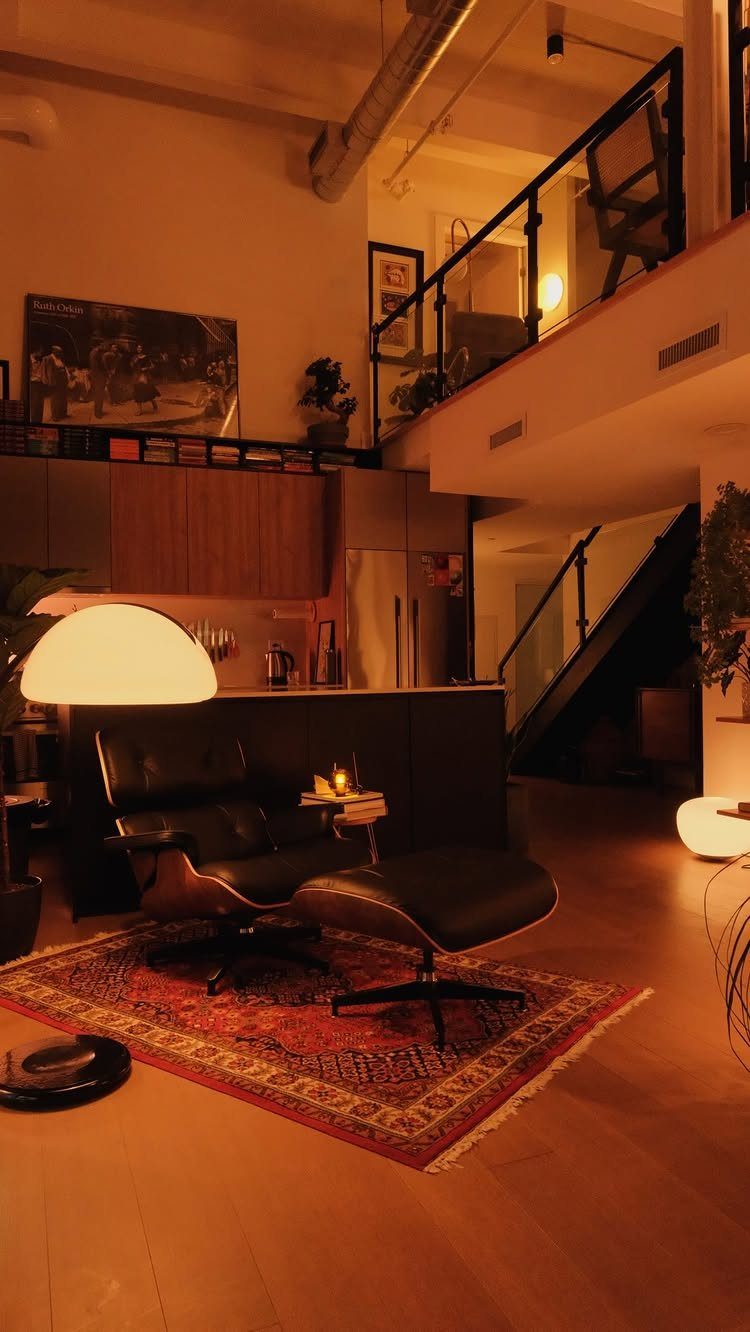 Black leather lounge chair and ottoman on a red patterned rug in modern loft
