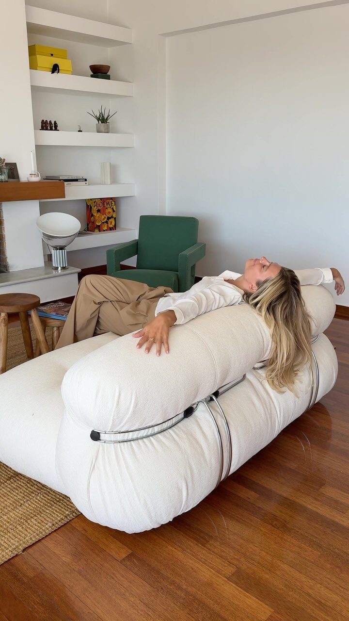 Woman lounging on a large, sculptural white modular sofa in a modern living room.