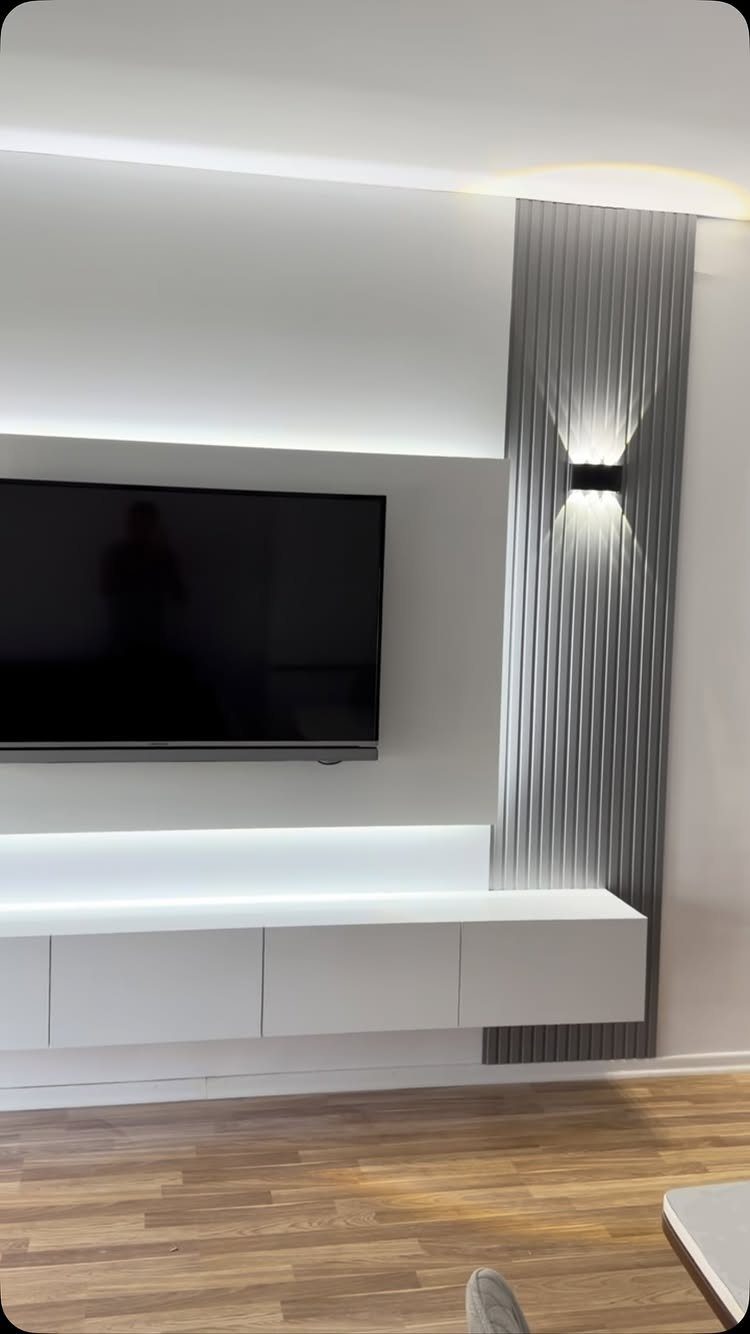 Modern living room wall with a black sconce light on grey slatted panels.