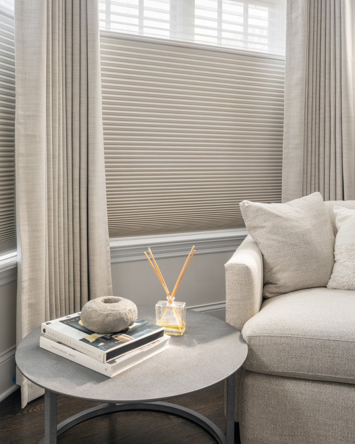 Beige cellular shades and floor-to-ceiling curtains in a modern living room setting.