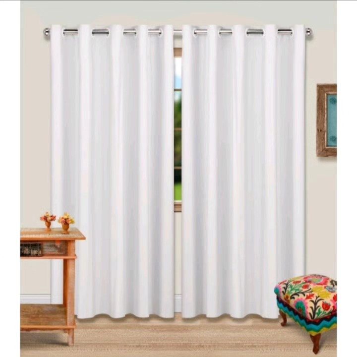 White grommet curtains hanging on a silver rod in a bright living room