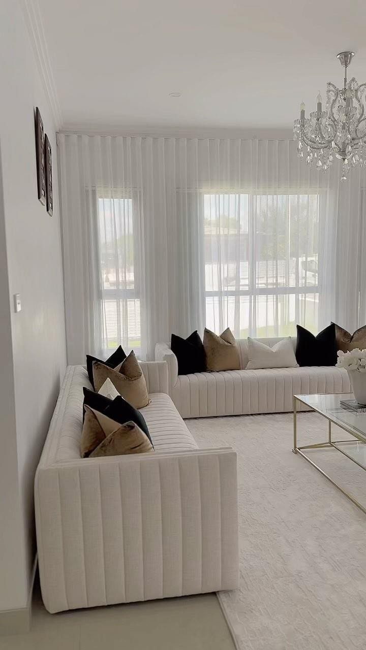 White sheer curtains covering large windows in a modern white living room