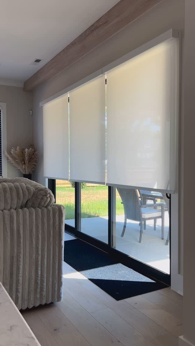 White sliding panel blinds on a large glass door in a modern living room.